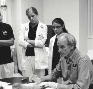 Dr. Bob Brier examines an arm from an Egyptian mummy with LIU Post students in the Medical Imaging Lab. By LIU Post PR
